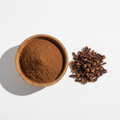 Cloves powder in a wooden bowl with whole cloves on white background