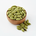 Whole green cardamom pods in a wooden bowl on white background