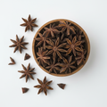 Whole star anise in a wooden bowl on white background
