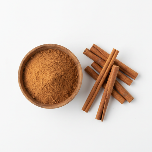 Cinnamon powder in a wooden bowl with cinnamon sticks on white background